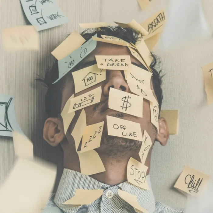 Homme au travail submergé par des notes autocollantes, illustrant le stress professionnel