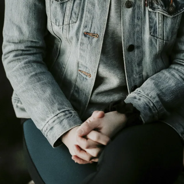 Mains crispées l'une contre l'autre, veste en jean