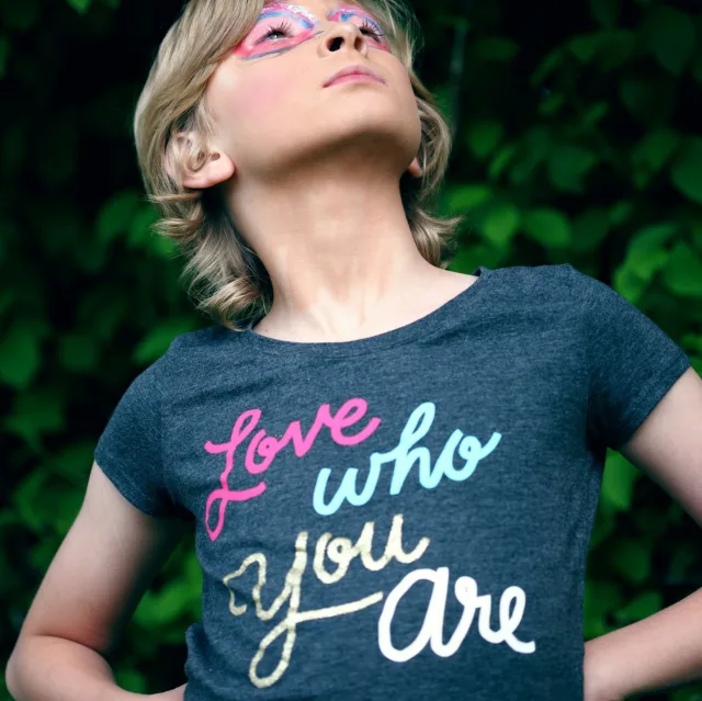 Enfant fier, tête levée, portant un t-shirt « Love who you are »