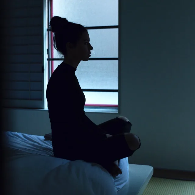 Silhouette assise et éveillée dans le noir, la nuit