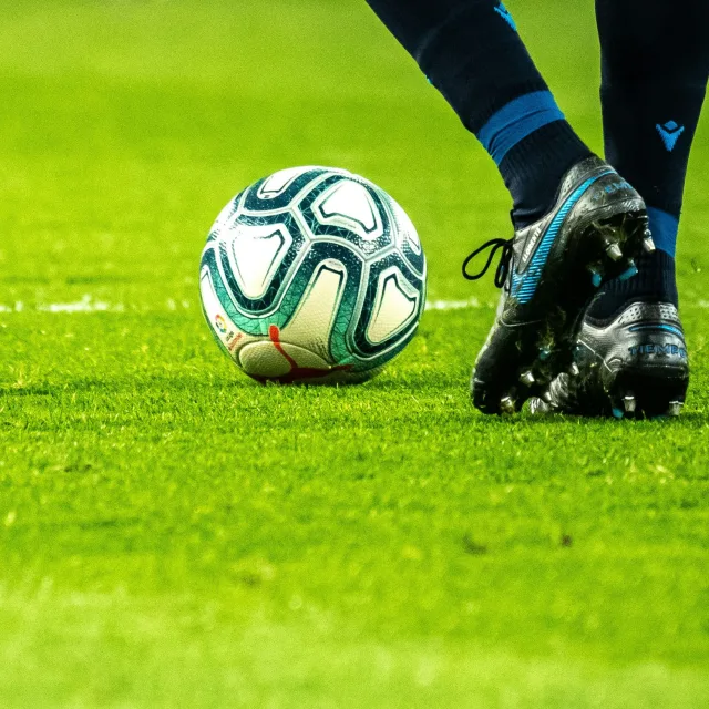 Ballon de football au sol devant des crampons, sur une pelouse
