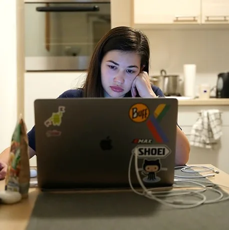 Jeune femme accoudée devant son ordinateur portable, l'air las